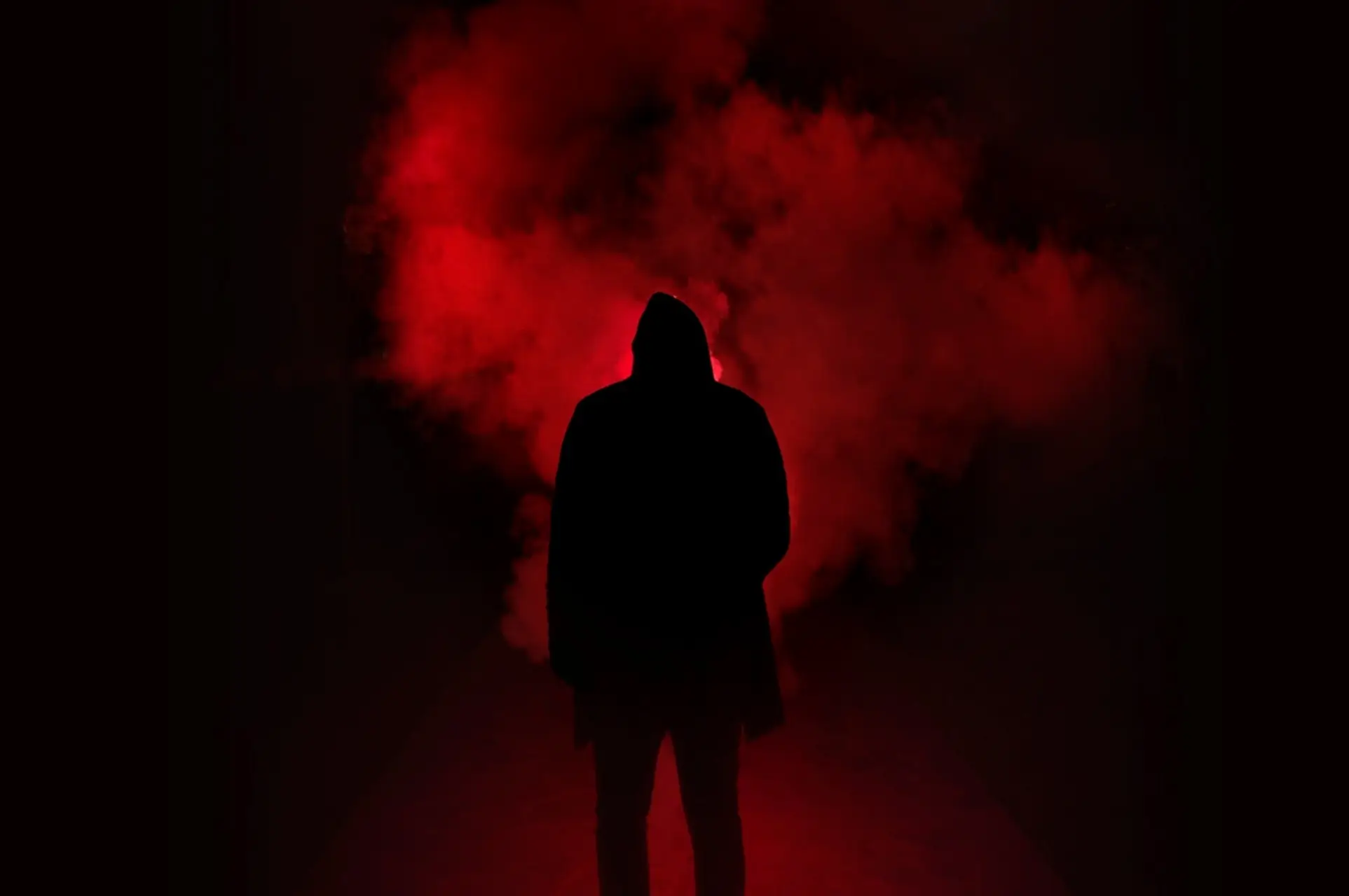 scary silhouette of a man wearing a cloak with red smoke behind him